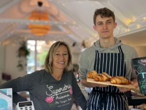 a woman cafe owner with young man assistant holding up croissants 